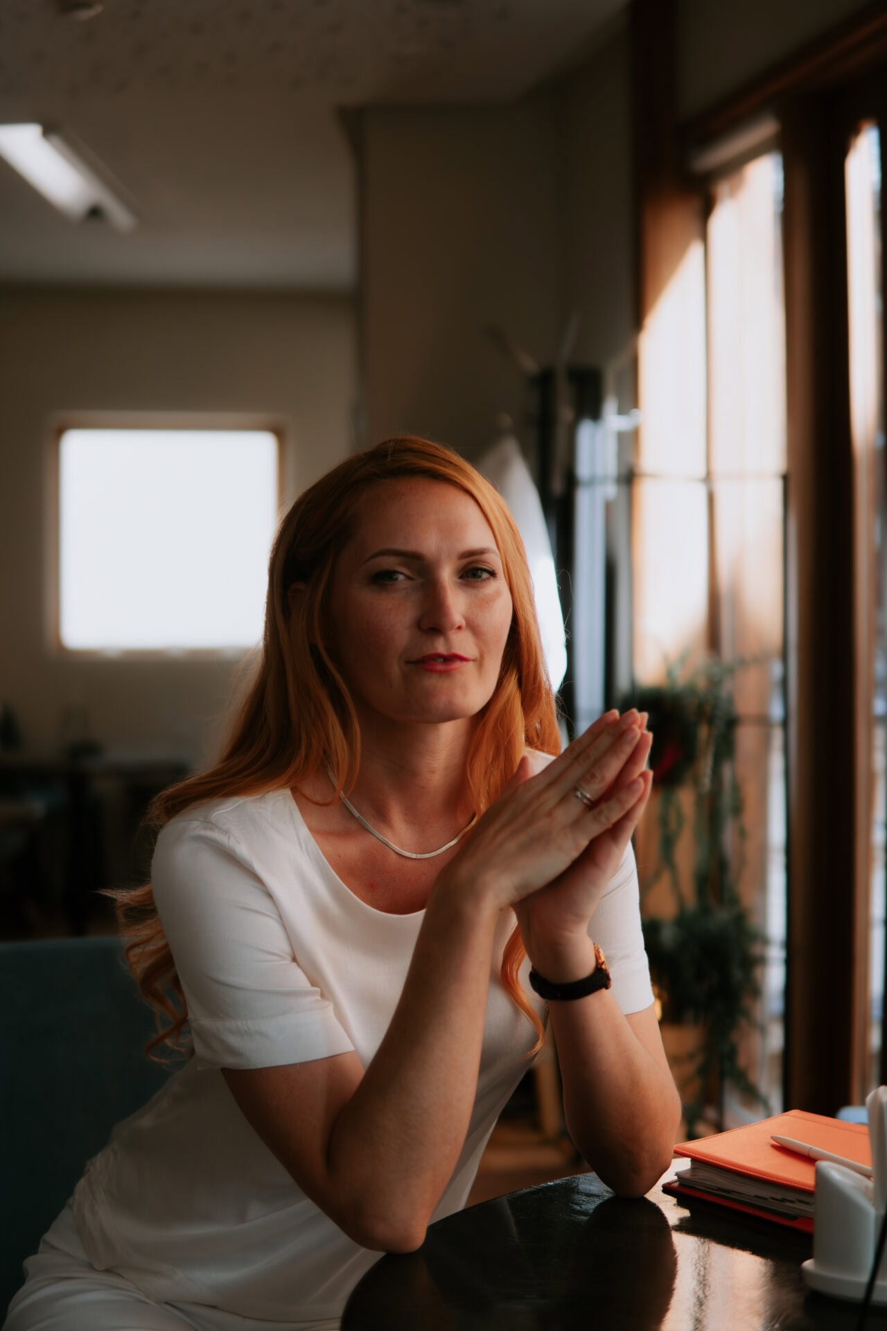 Baltijas sieviete biznesa vide, klusā kafejnīcā ar dabu un saulesgaismu.